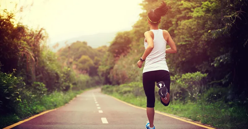 Image d'une personne, une femme faisant la course à pieds sur une petite route.